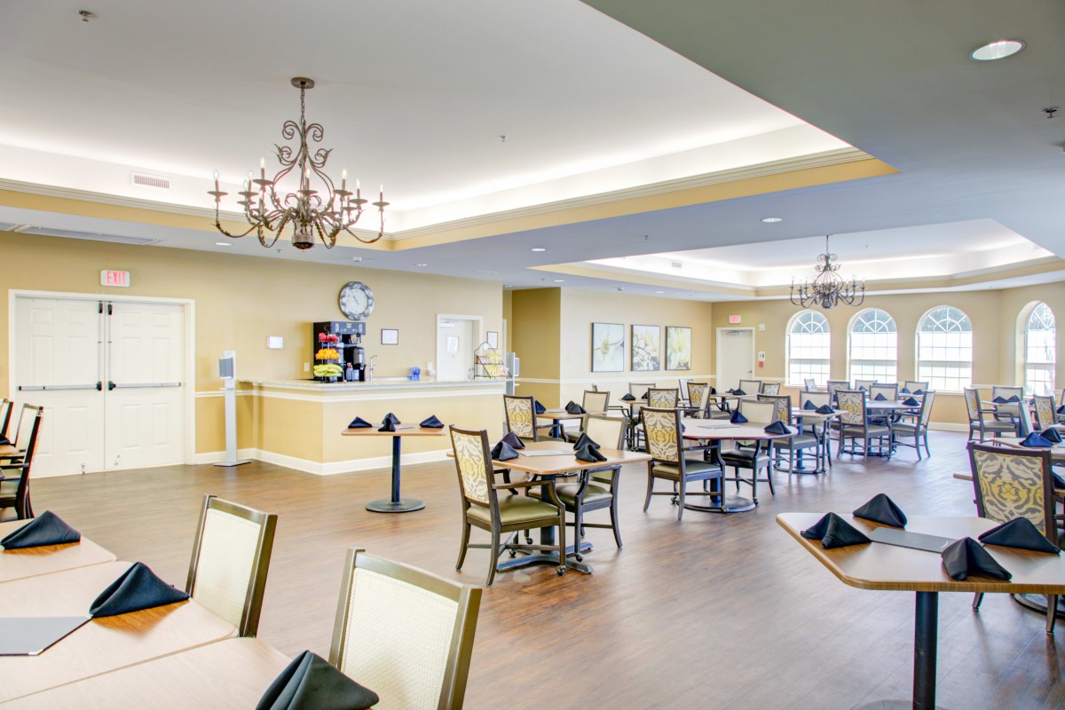 A spacious dining room with elegant chandeliers and neatly arranged tables and chairs.