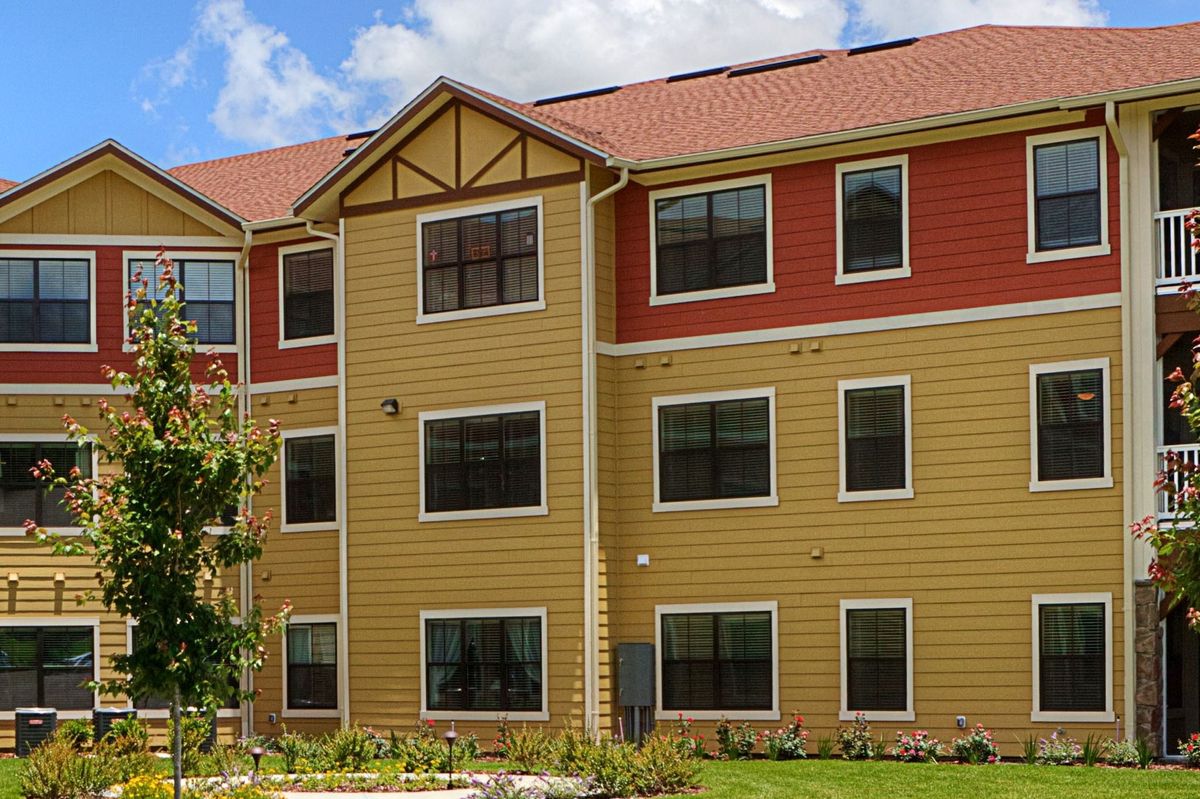 A three-story residential apartment building with multiple windows and a colorful exterior.