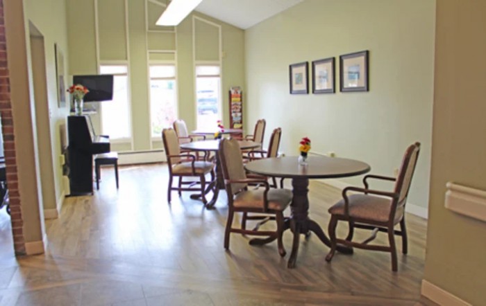 A bright and spacious dining area with wooden tables and chairs, adorned with wall art and large windows.