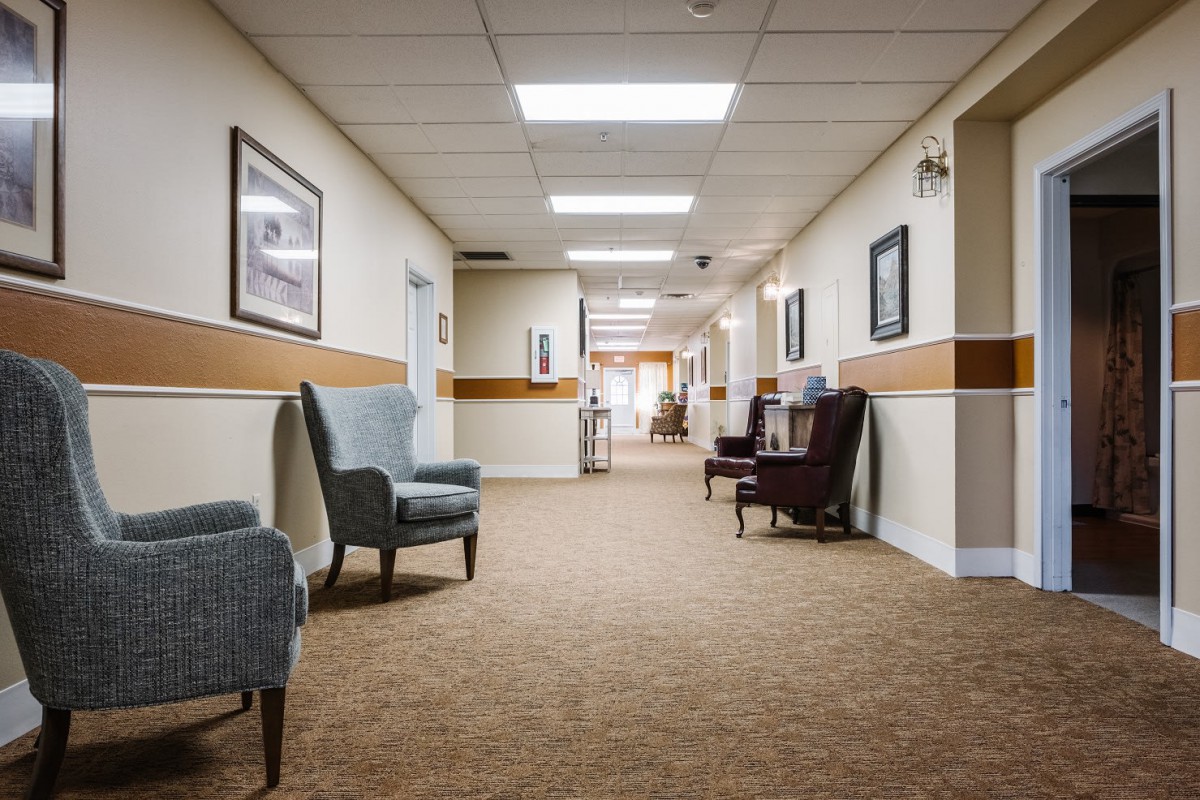 A well-lit hallway with comfortable seating and framed pictures on the walls.