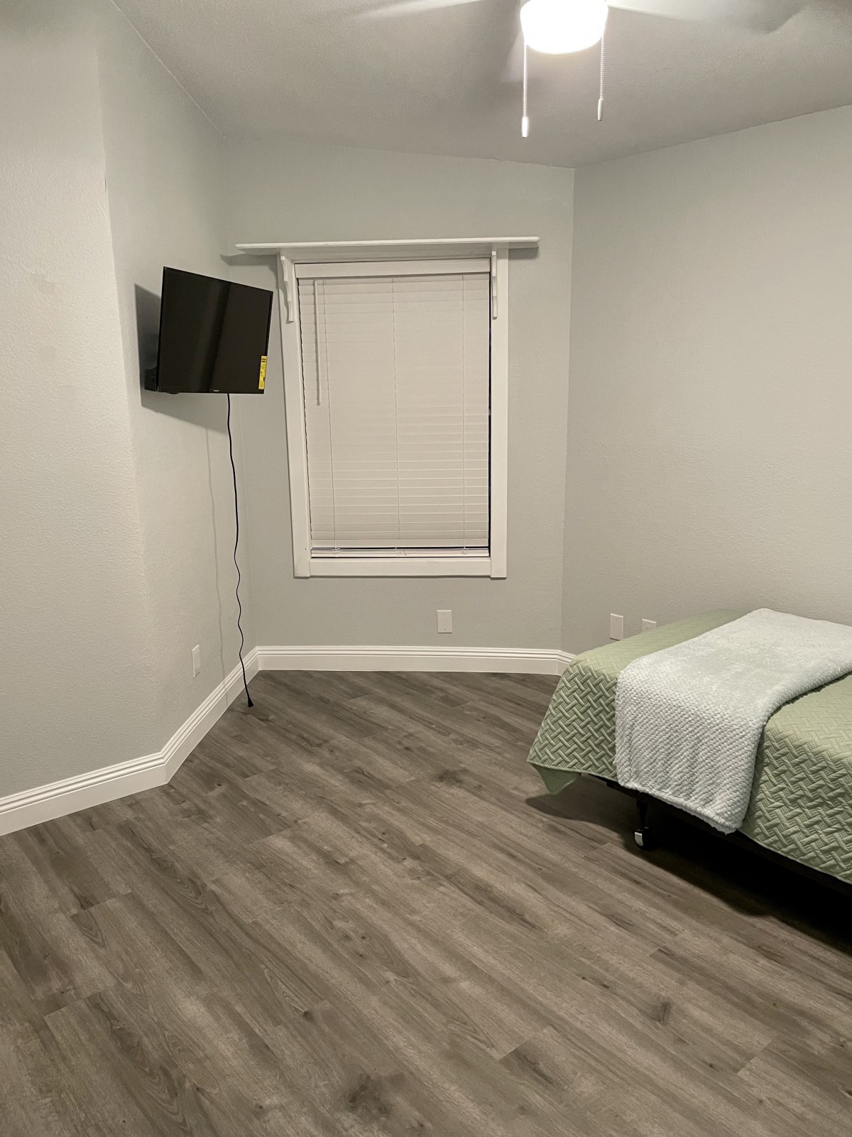 A minimalist bedroom with a single bed and wall-mounted TV.
