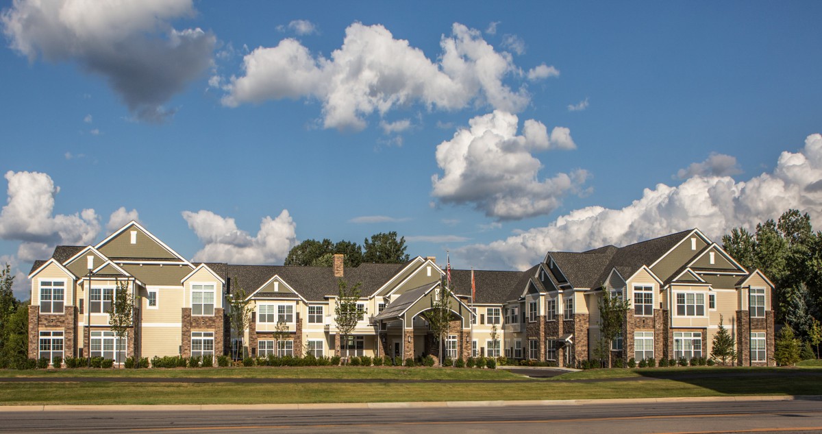 A picturesque suburban residential building under a partly cloudy sky.
