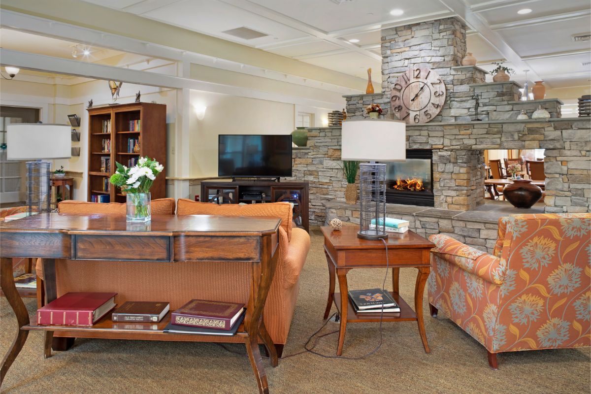 A cozy living room with orange furniture, a stone fireplace, and a large TV.