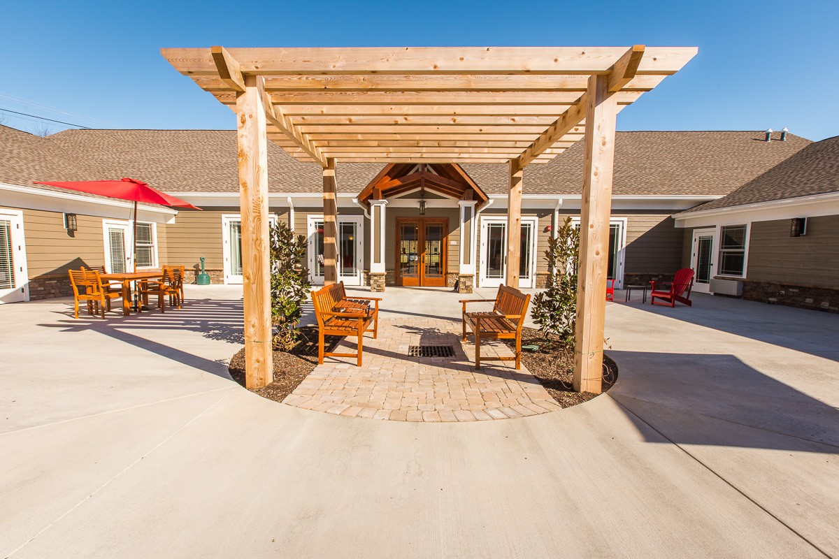 A beautifully designed outdoor patio area with a wooden pergola and seating.