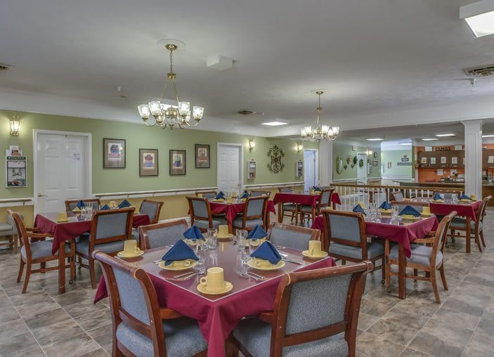 A well-organized dining room with neatly arranged tables and chairs, featuring chandeliers and elegant decor.