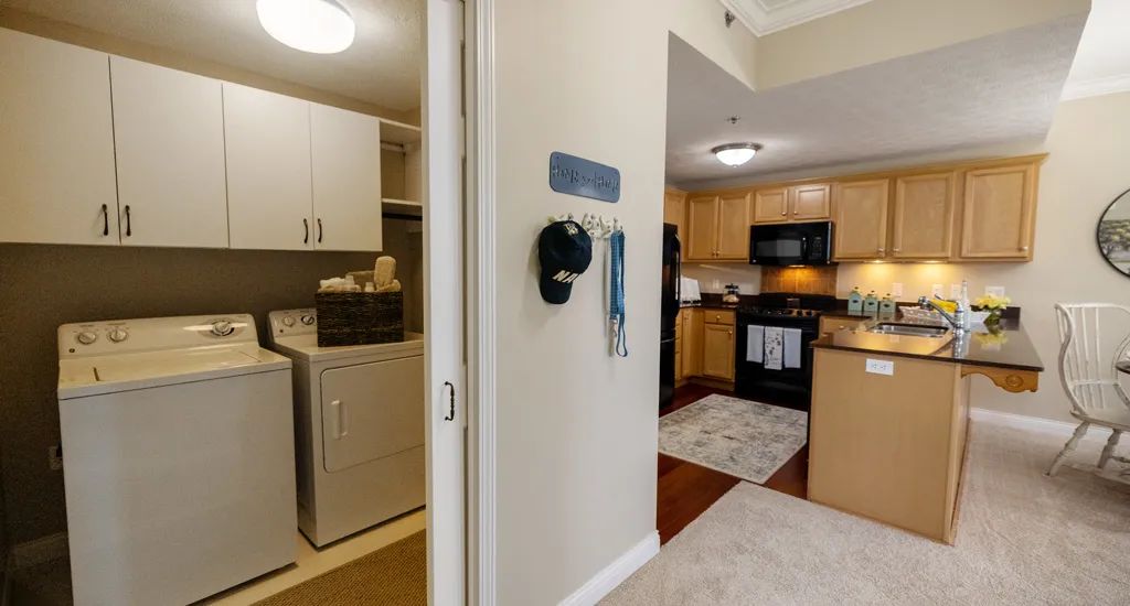 A view of a home's interior showcasing the laundry room with a washer and dryer, adjacent to a kitchen equipped with modern appliances.