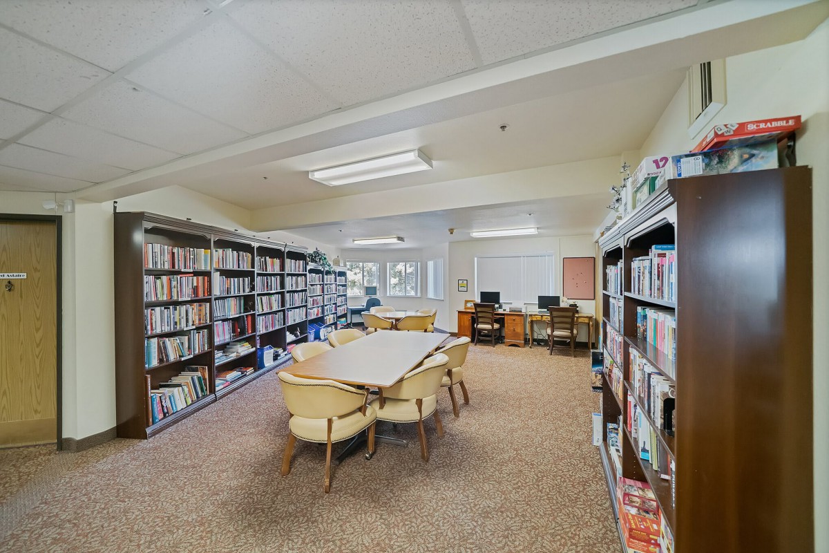 A quiet library room with bookshelves, tables, and chairs for reading and study.