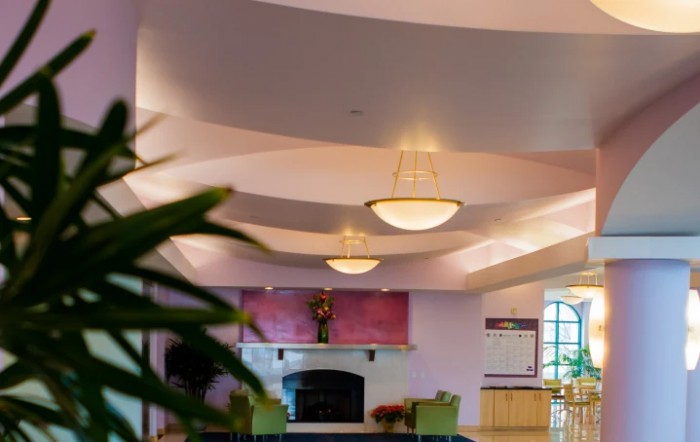 A well-lit lobby with chandeliers, featuring a fireplace and comfortable seating.