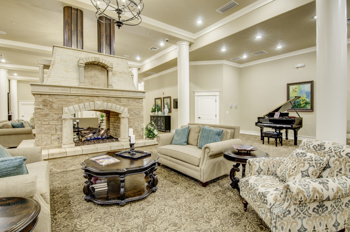 A luxurious living room with elegant furniture, a grand piano, and a large fireplace.
