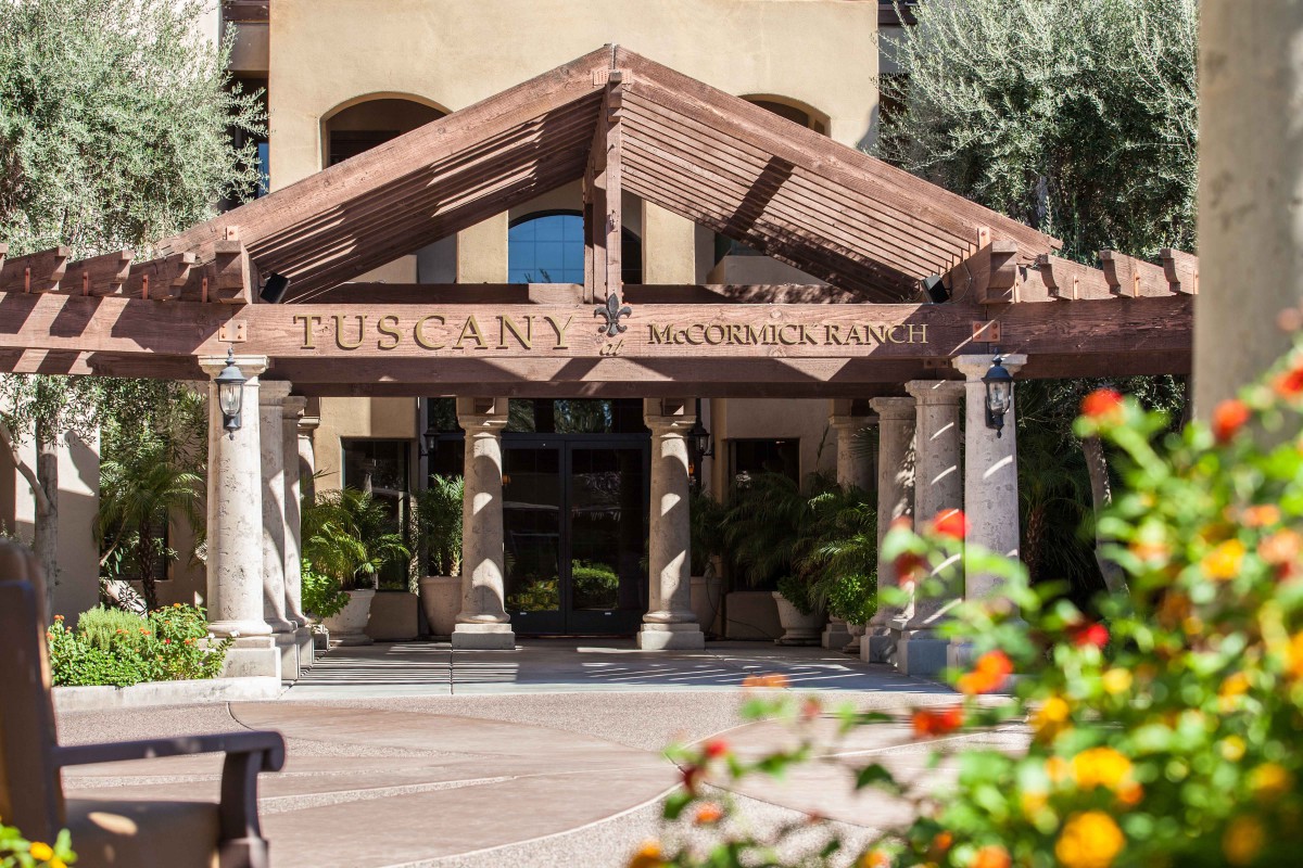 Entrance to the Tuscany-themed hotel with columns and lush greenery.