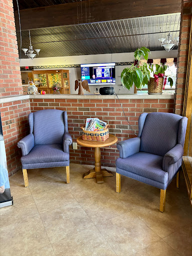 A cozy seating area featuring two blue chairs and a small table adorned with a decorative basket, set against a rustic brick wall.