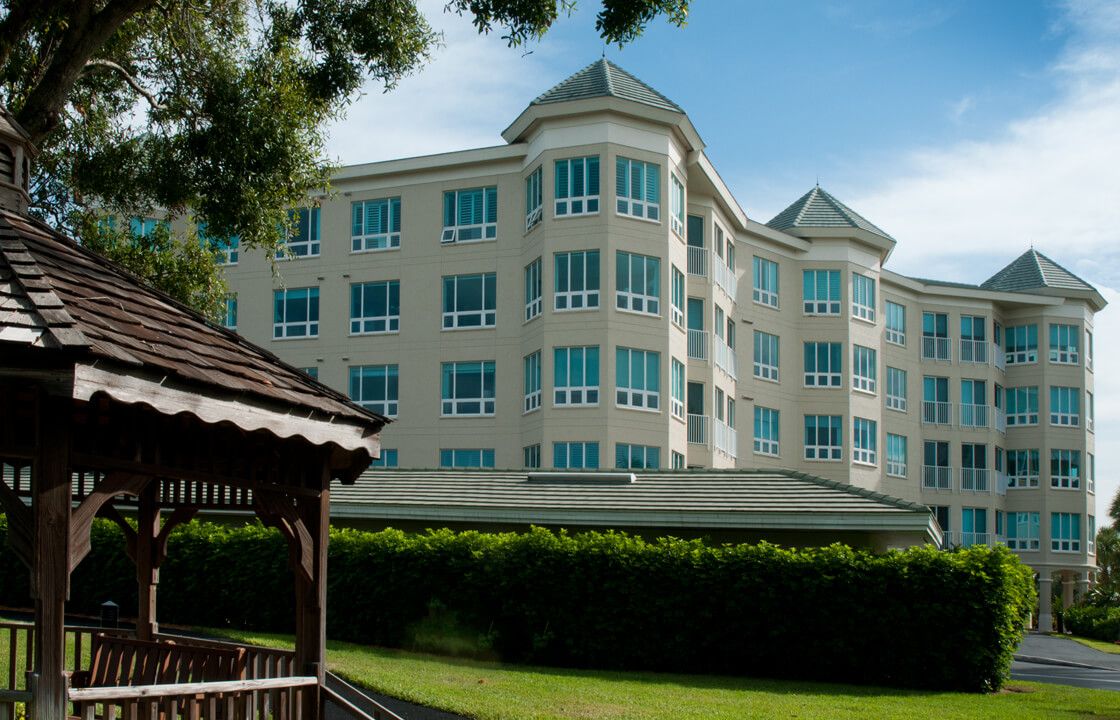 A modern residential building with large windows and a well-maintained garden in the foreground.
