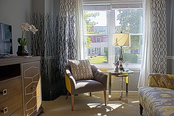A cozy sitting area with a chair, side table, and lamp by the window.