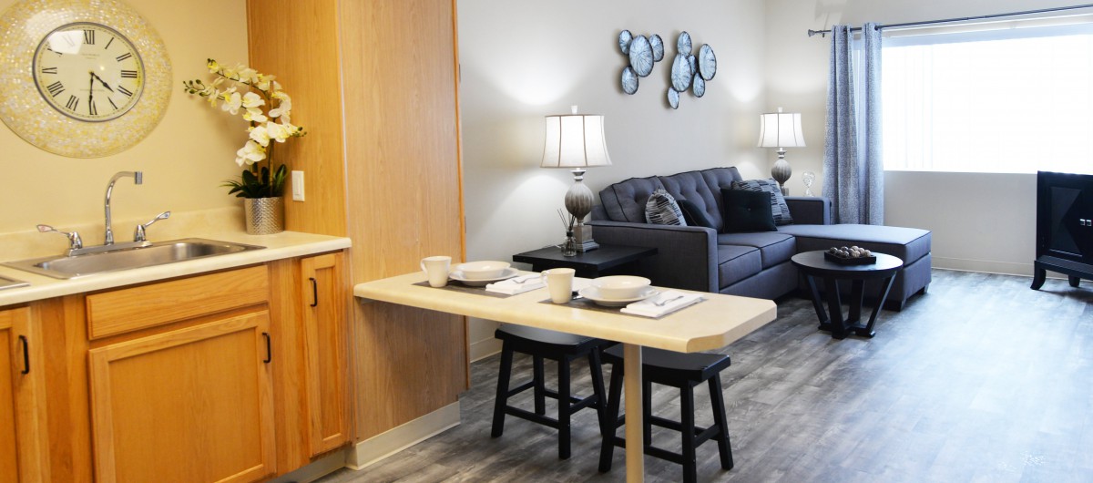 A modern living space featuring a small dining area with two stools and a cozy living room with a sofa.