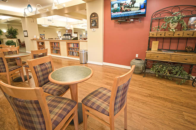 A cozy dining area with a table and chairs, featuring a wooden floor and a television mounted on the wall.