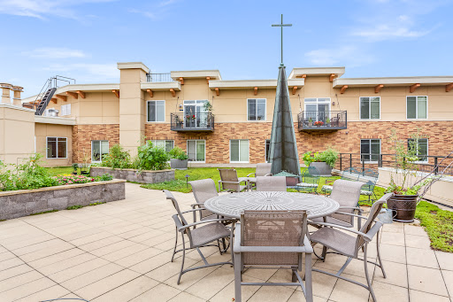 A serene outdoor seating area featuring modern furniture and lush landscaping, complemented by a striking cross sculpture.