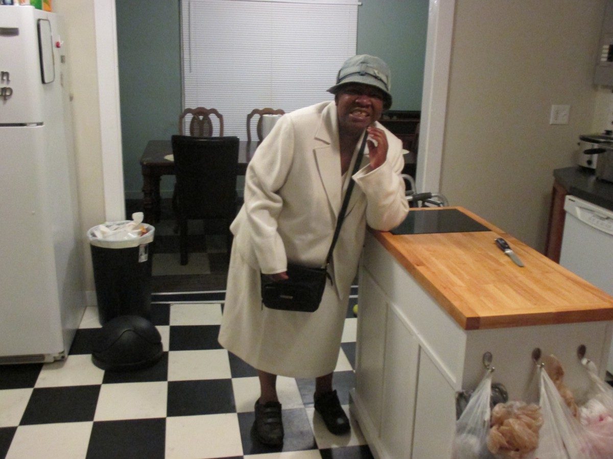 A person dressed warmly in a coat and hat standing in a kitchen.