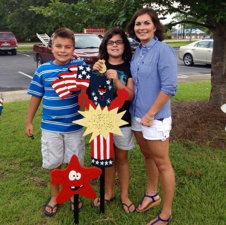 A family posing together outdoors with a patriotic-themed decoration.