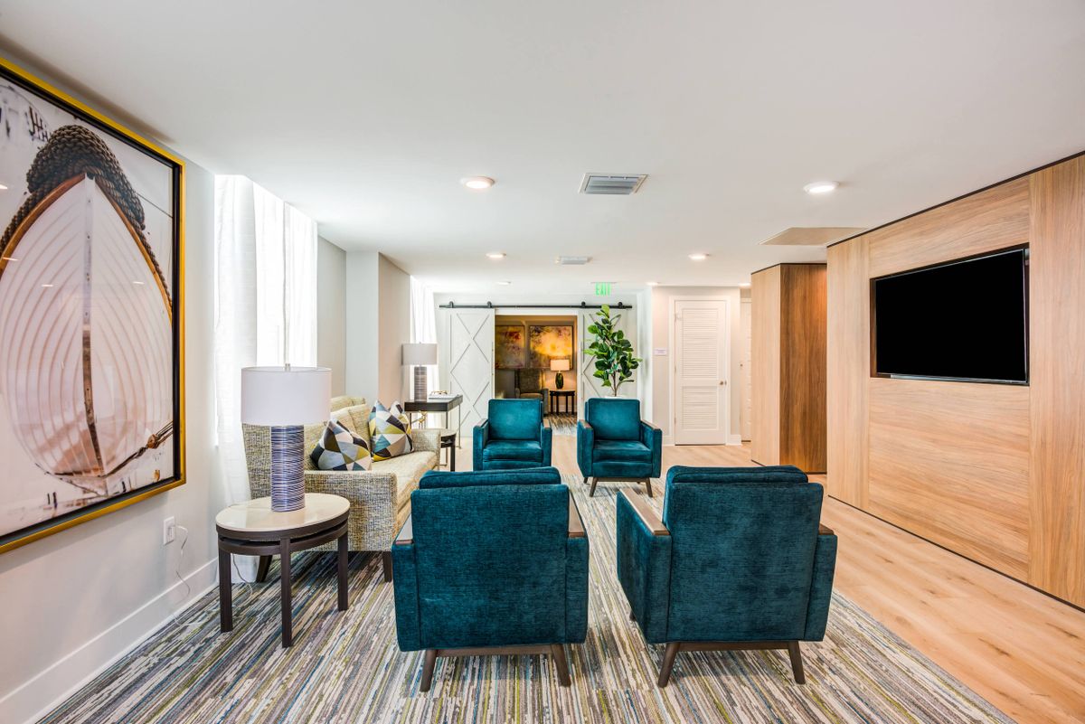 A modern living room with teal armchairs and contemporary decor.