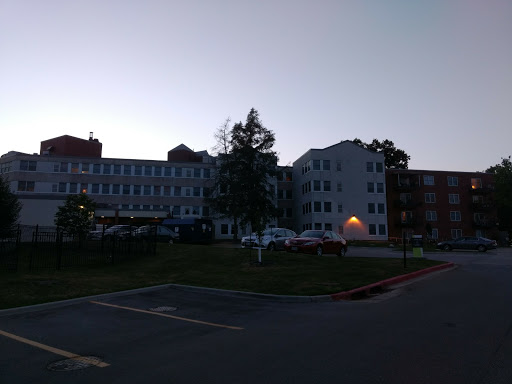 A view of a hospital building during the evening, featuring trees and a parking area.