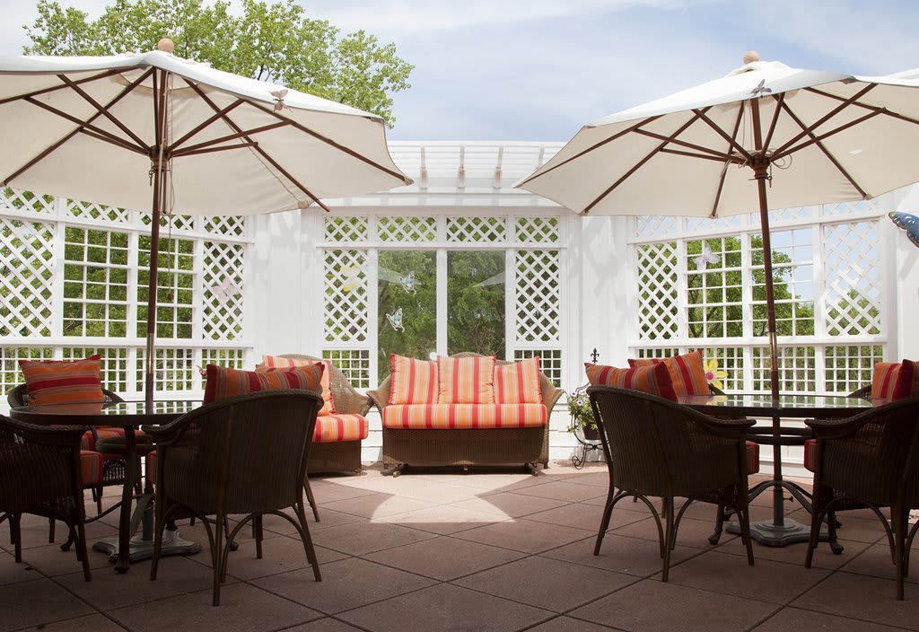A cozy outdoor patio with wicker furniture and umbrellas on a sunny day.