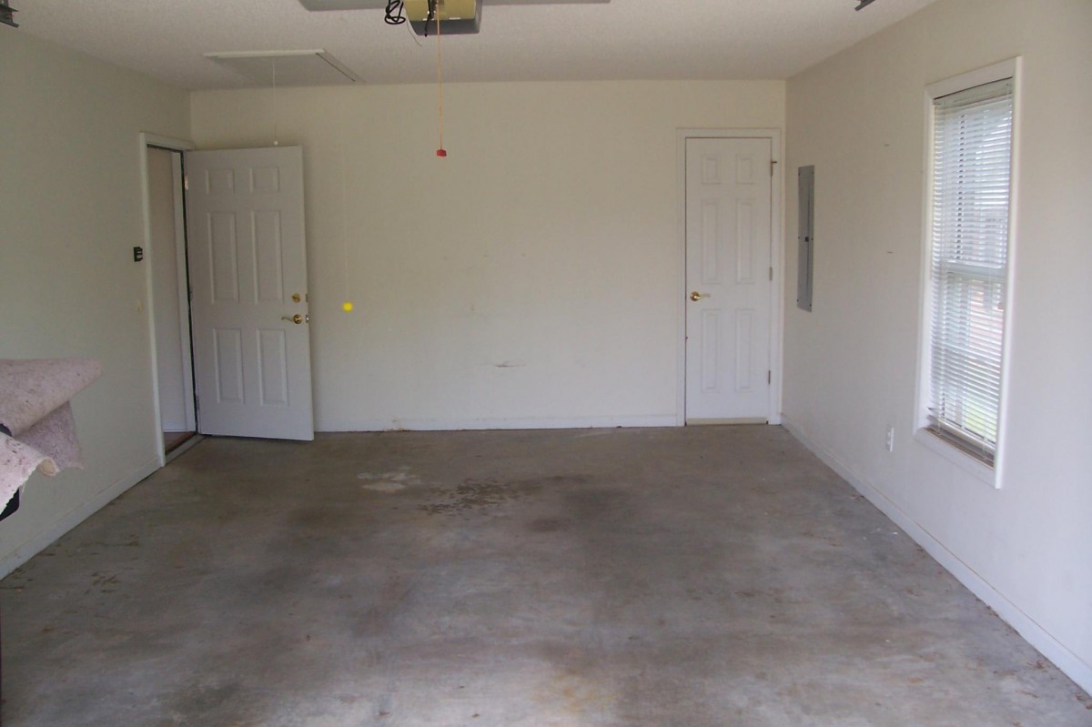 An empty garage with concrete flooring and two doors.