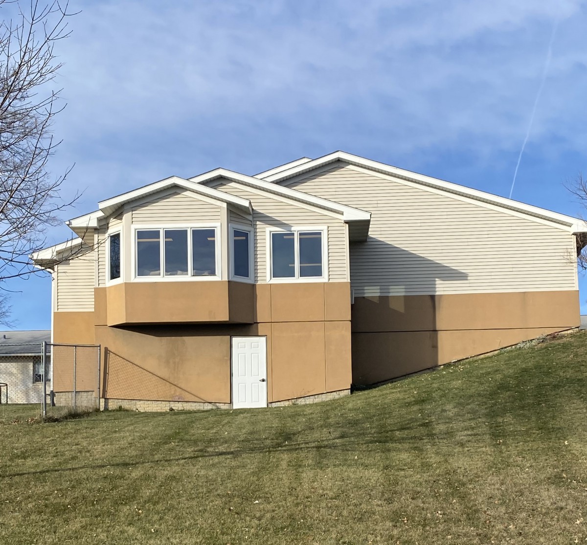 A residential house with a sloping lawn and a clear blue sky.