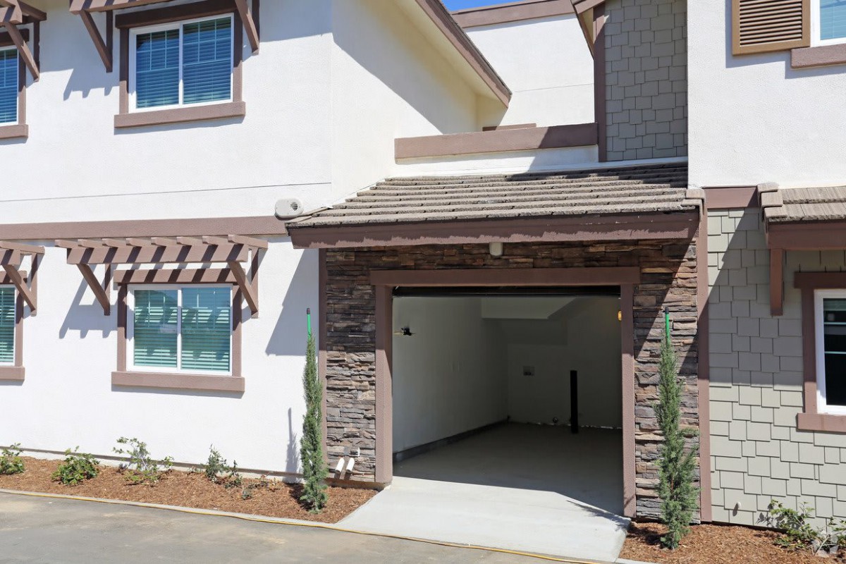 A modern house with an open garage and a small driveway.