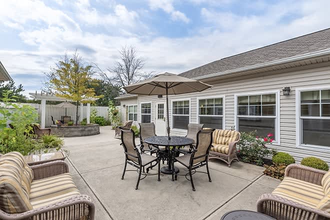 A cozy patio area with a round table, chairs, and an umbrella set against a one-story house.