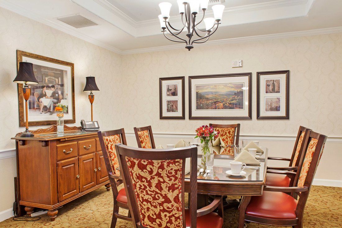A well-appointed dining room features a large wooden table surrounded by intricately designed chairs, with elegant artwork and a chandelier enhancing the ambiance.