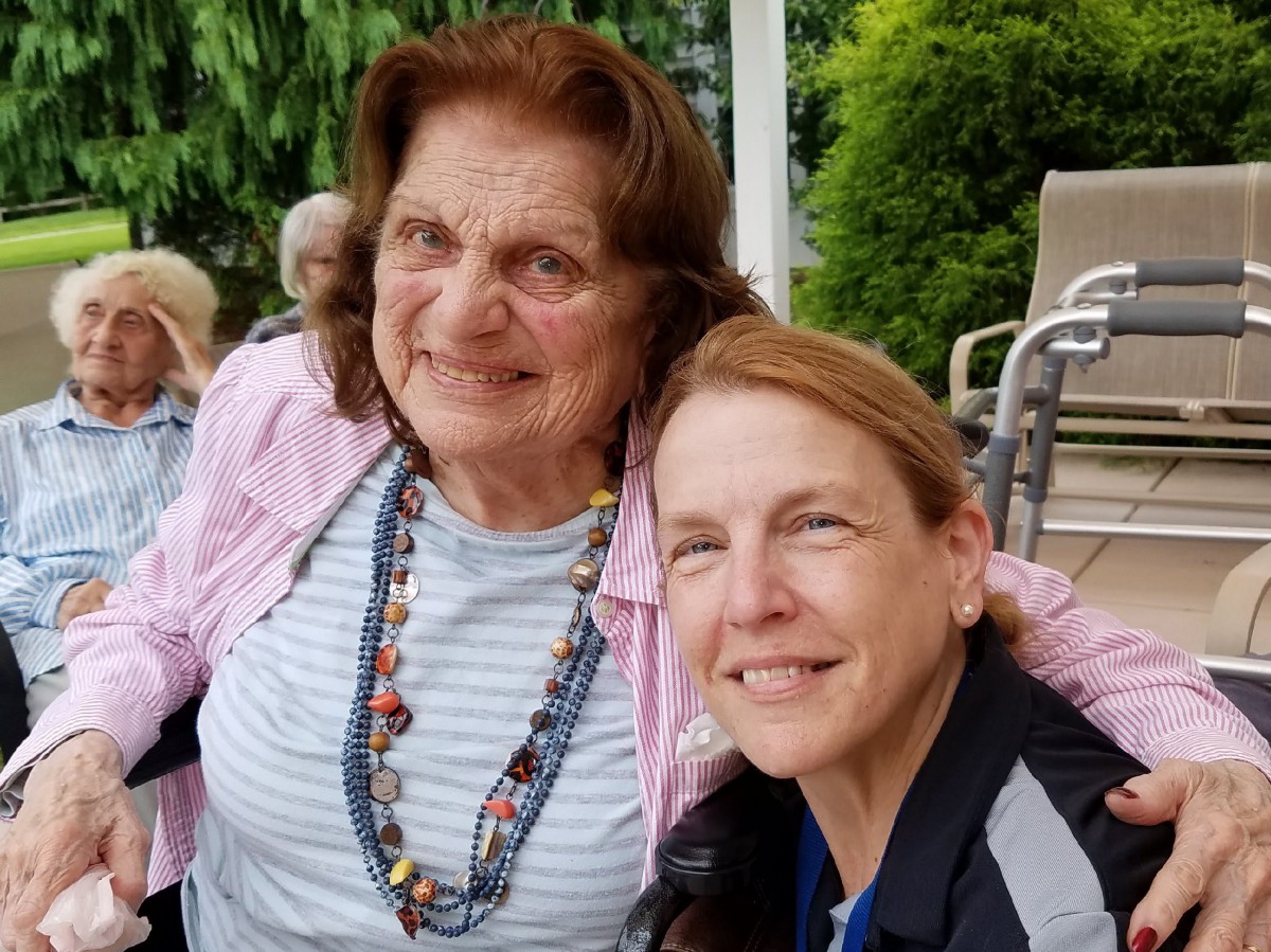 Two women smiling together in an outdoor setting.