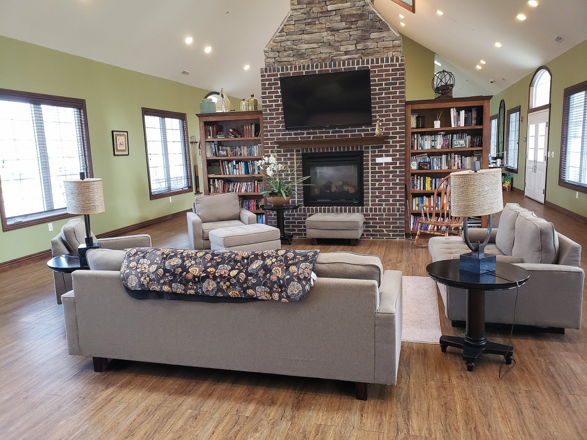 A cozy living room with a stone fireplace, flanked by bookshelves and comfortable seating.