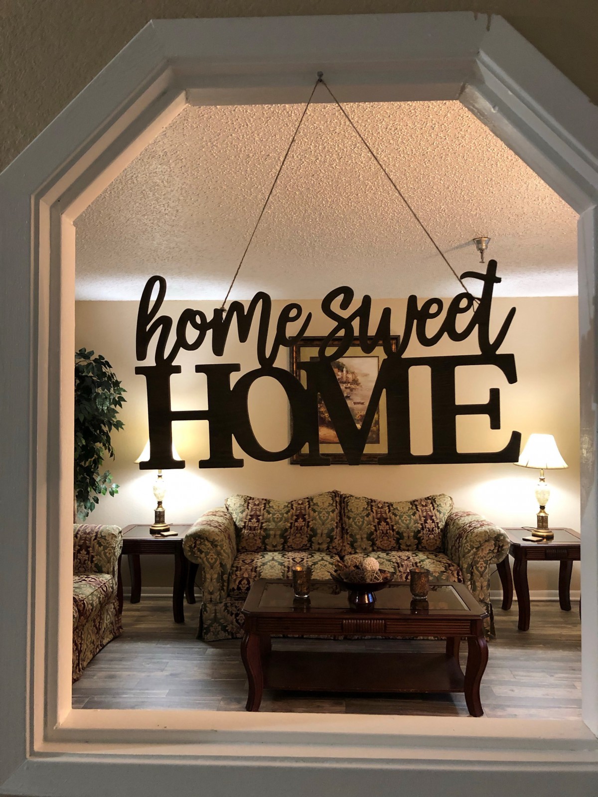 A cozy living room with a 'Home Sweet Home' sign hanging in the entrance.