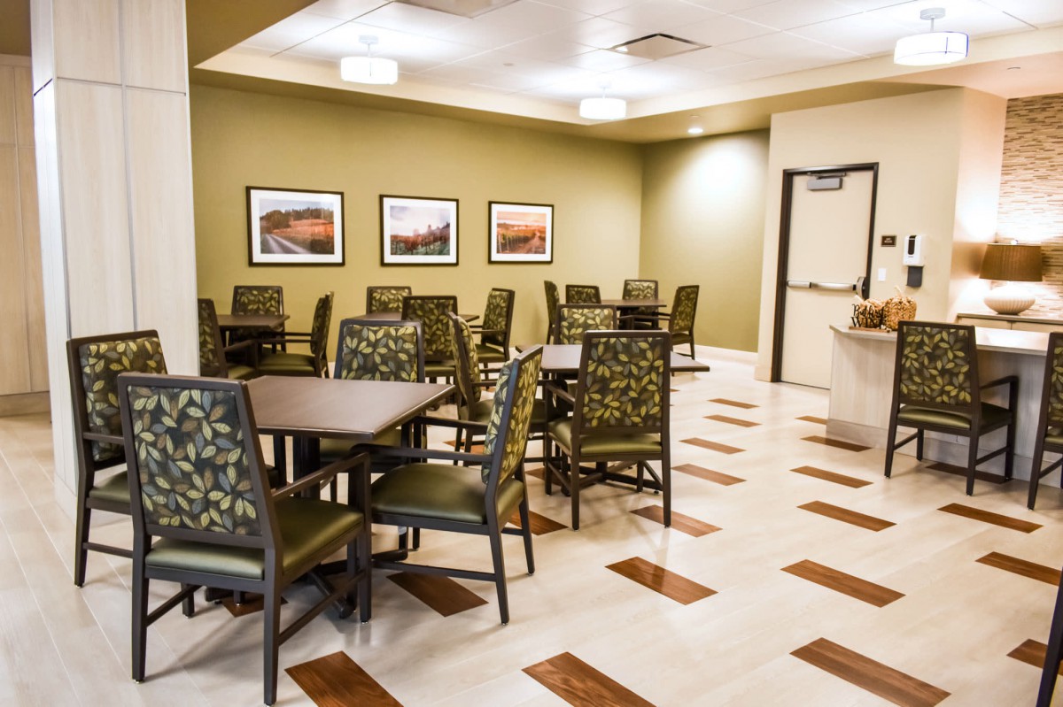 A clean and empty dining area with several tables and chairs, decorated with framed artwork on the walls.