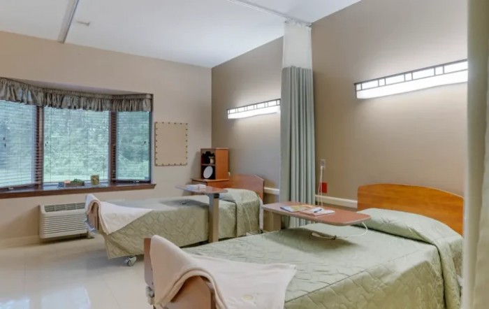 A clean and well-organized hospital room with two beds and medical equipment.