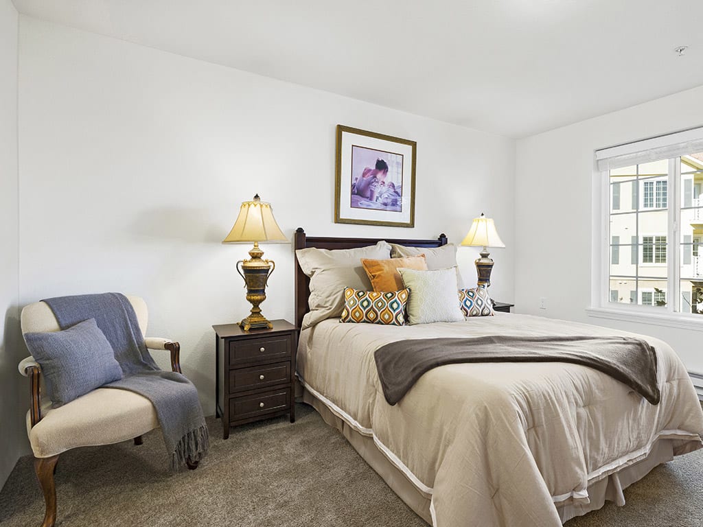 A cozy and well-decorated bedroom with a comfortable bed, bedside lamps, and artwork on the wall.