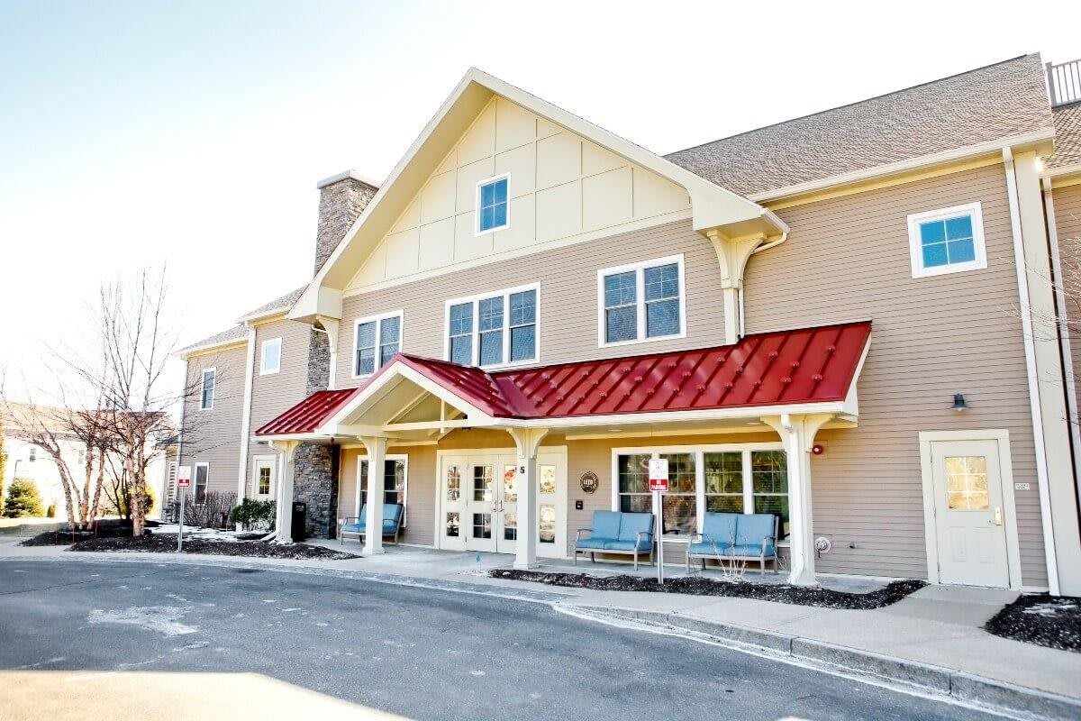 A residential building with a red roof and beige siding.
