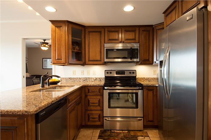 A modern kitchen featuring stainless steel appliances, wood cabinets, and granite countertops.
