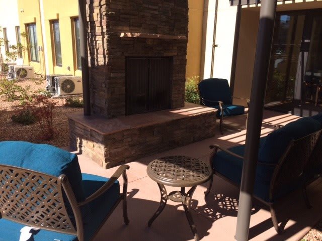 A cozy outdoor patio with comfortable seating around a stone fireplace.