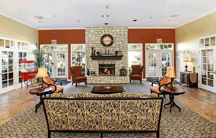 A cozy living room with a central stone fireplace and elegant furniture arrangement.