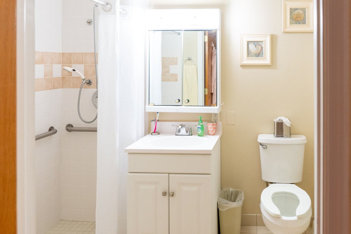 A small, clean bathroom with a shower, sink, and toilet.