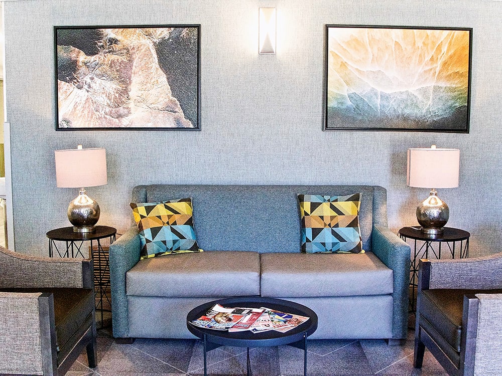 A cozy living room with a blue sofa, colorful pillows, and wall art.
