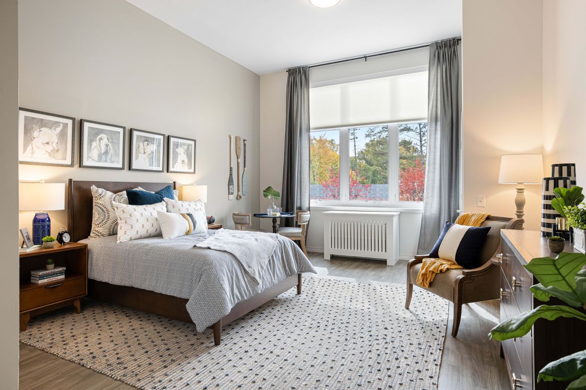 A modern and cozy bedroom with stylish decor, featuring a large window and comfortable furnishings.