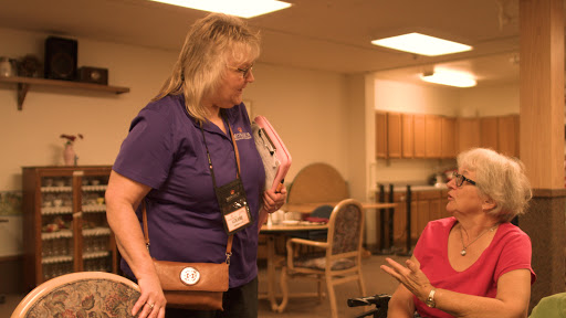 A caregiver engages in a warm conversation with an elderly woman at a community center.