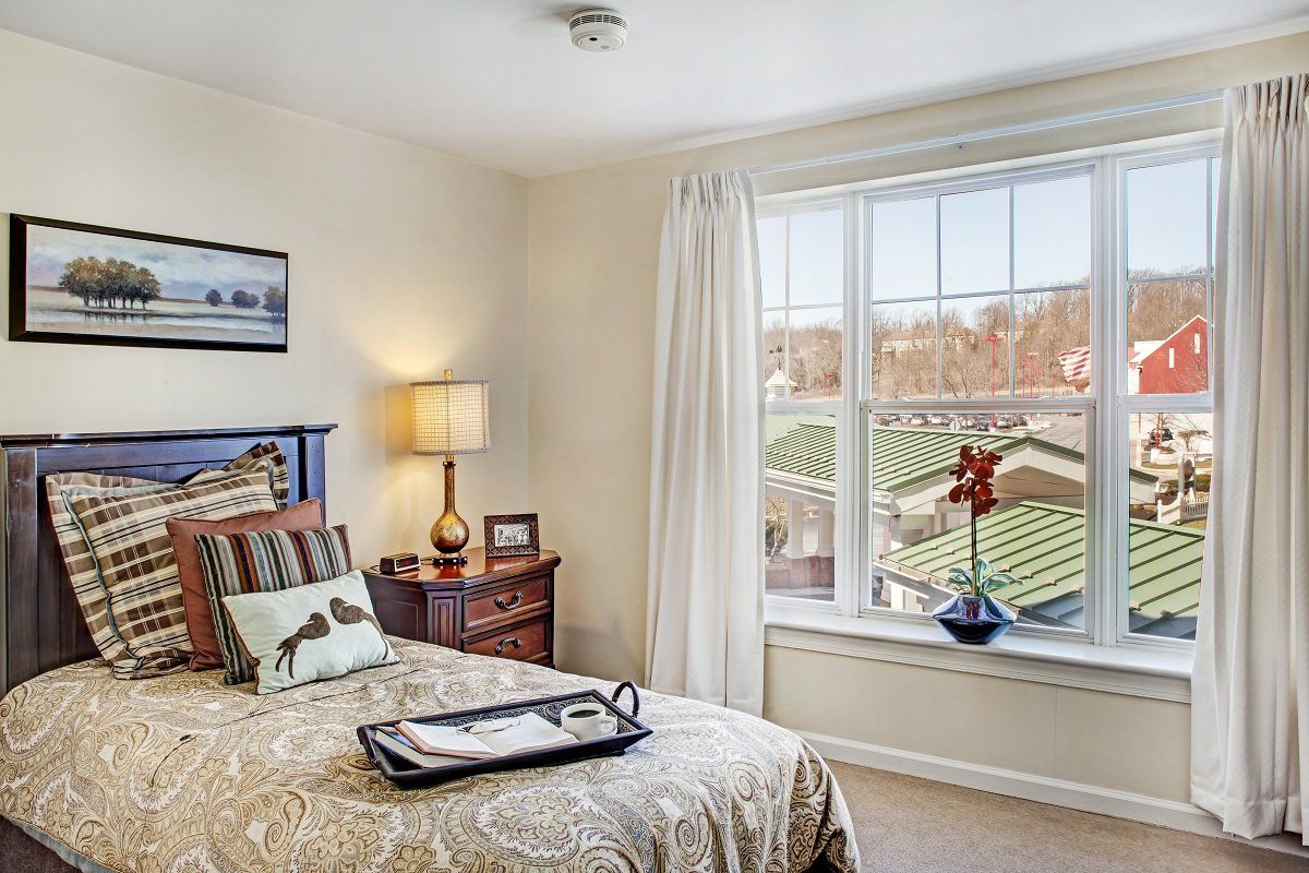 A cozy and well-decorated bedroom with a large window overlooking the outdoors.