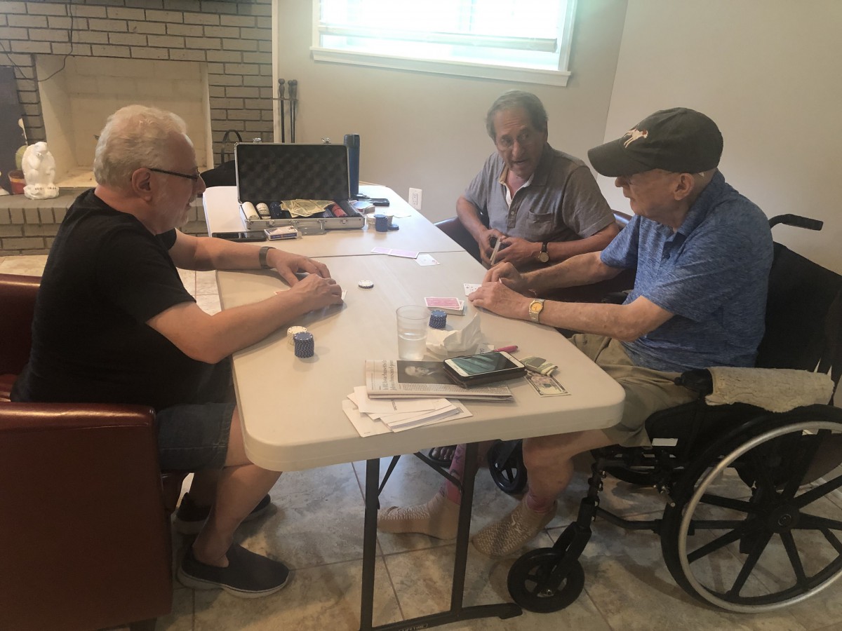 A group of elderly individuals playing cards at a table inside a room.