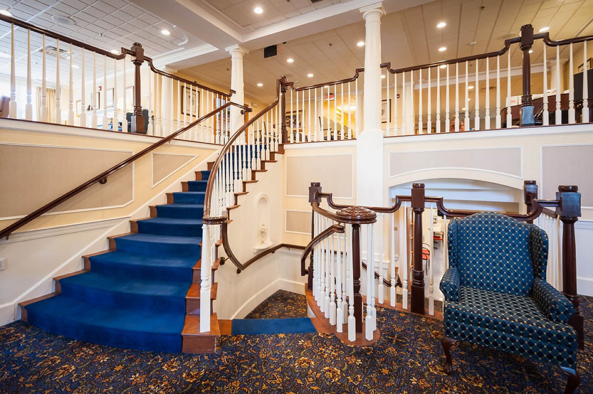 A grand staircase with a blue carpet in an elegant lobby setting.