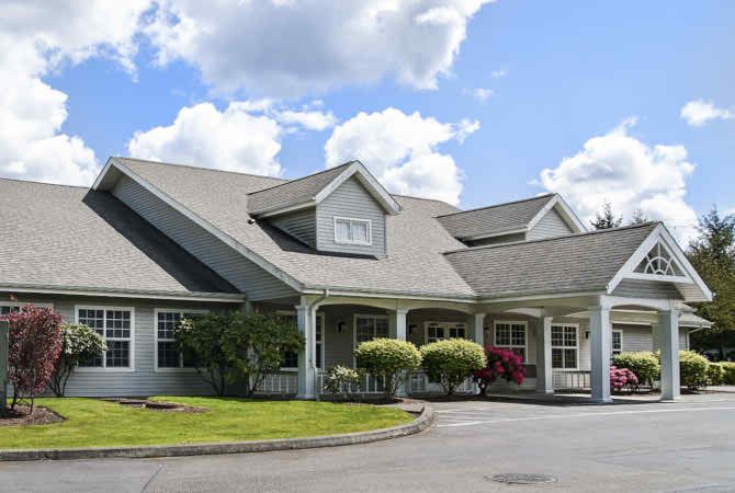 A charming residential house with a well-maintained front yard under a partly cloudy sky.