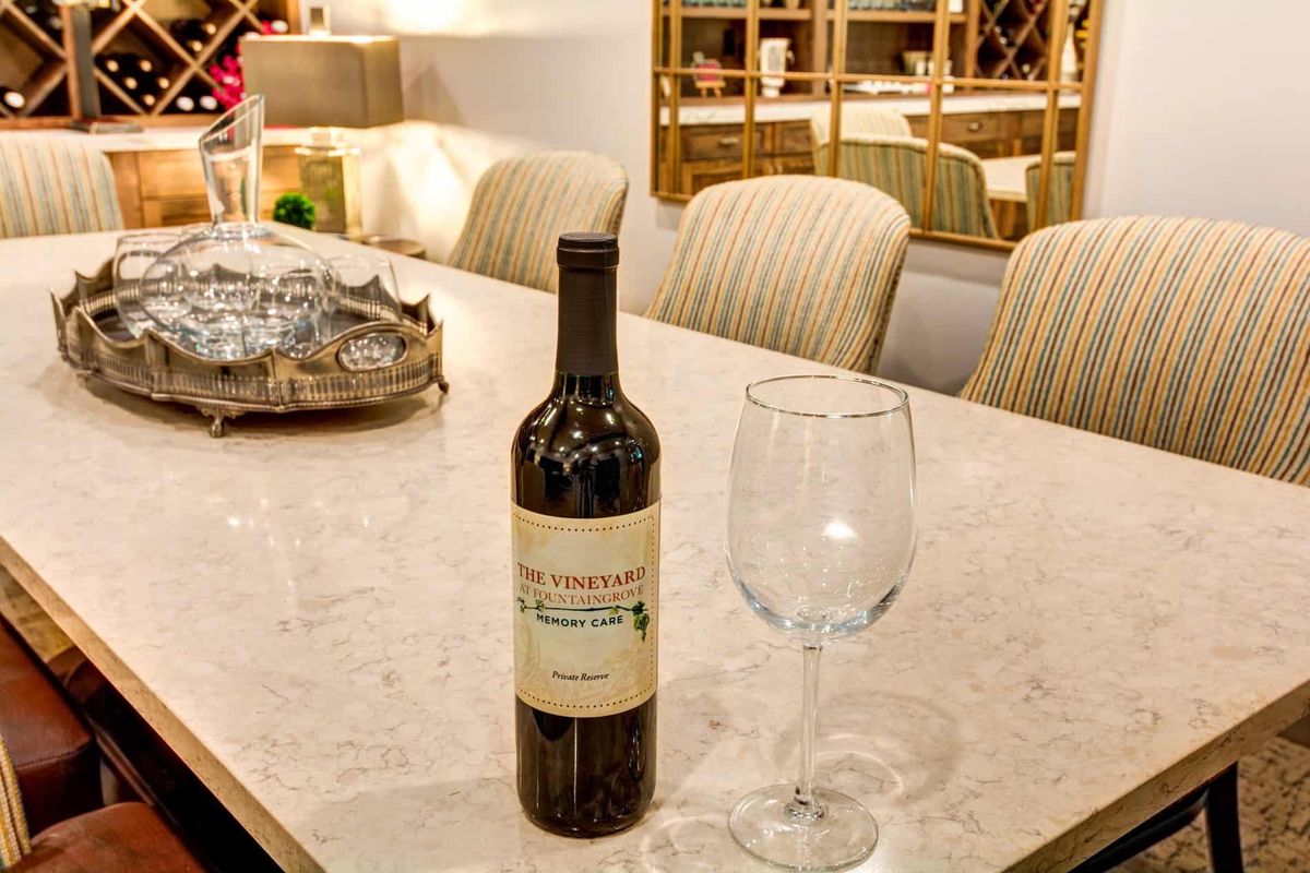 A bottle of wine and an empty wine glass on a dining table in an elegant setting.