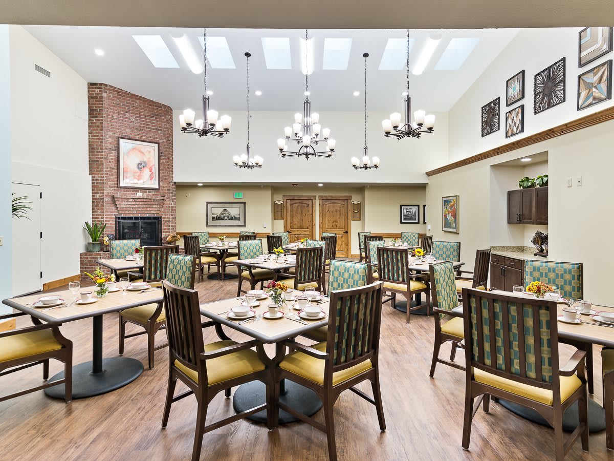 A well-lit dining room with elegant chandeliers, neatly arranged tables and chairs, and stylish decor.